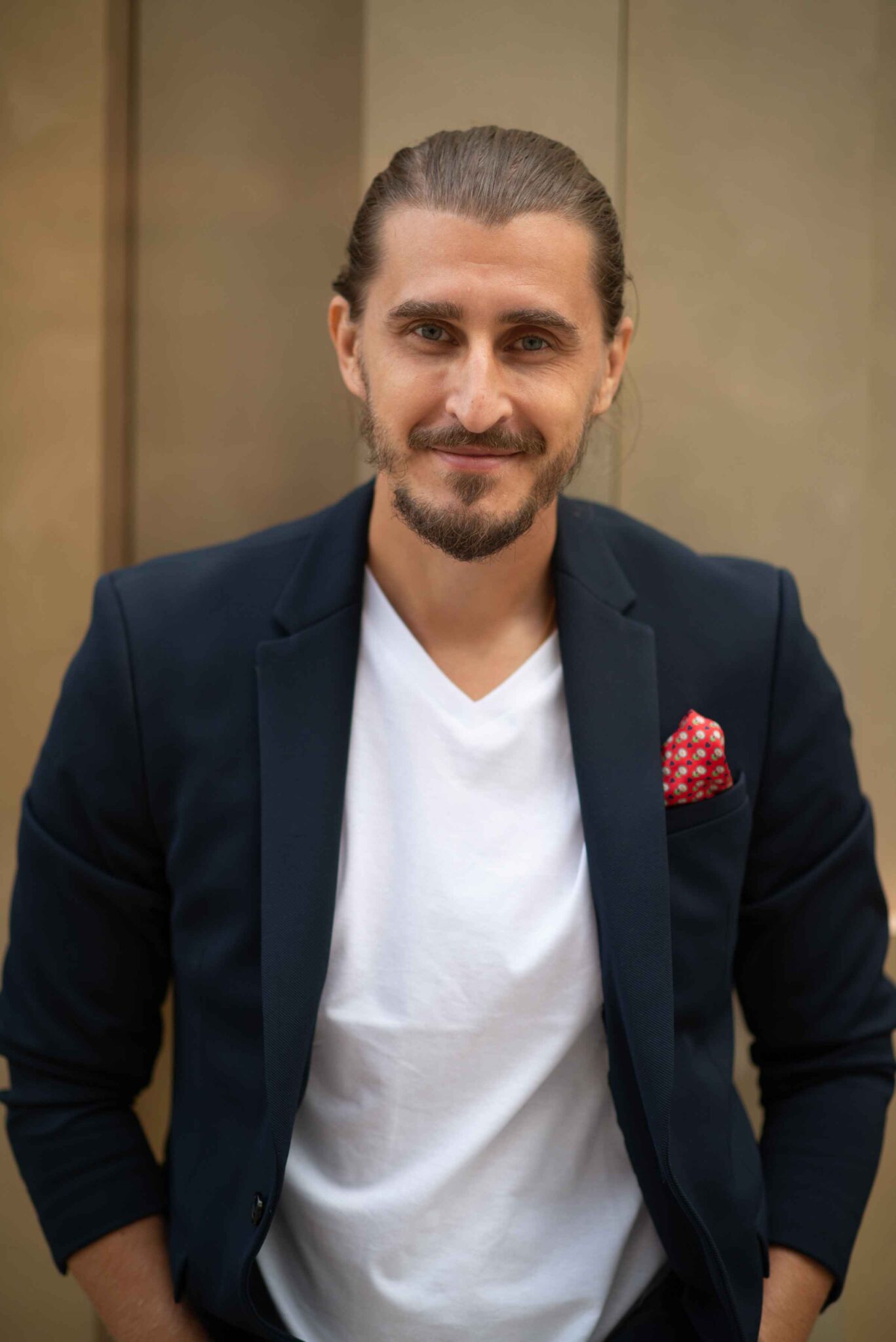 A professional headshot of author Artem Gonchakov wearing a dark blazer, white t-shirt, and a red patterned pocket square, smiling with a neutral background.