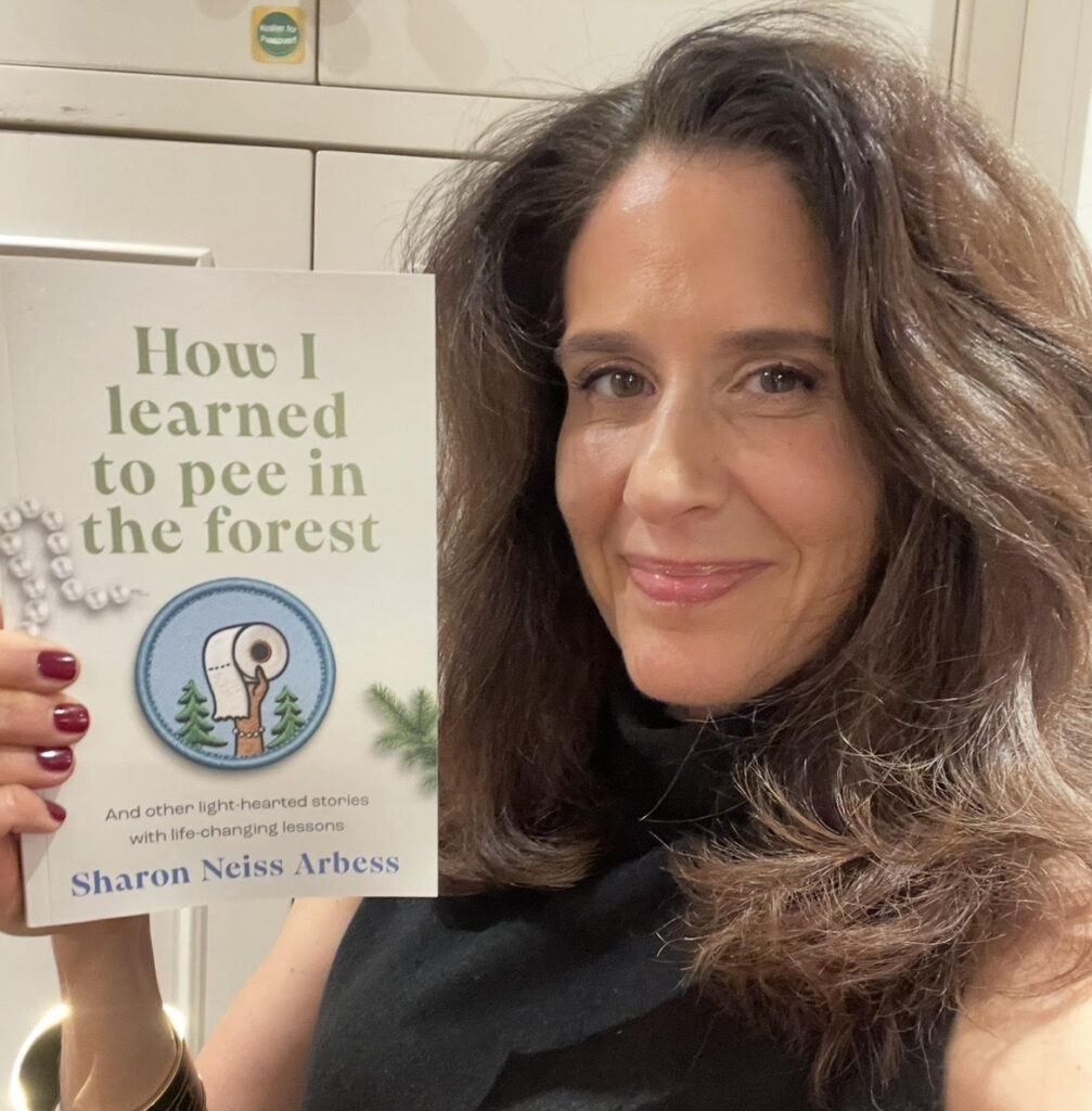 Author Sharon Neiss Arbess smiling while holding her book How I Learned to Pee in the Forest.